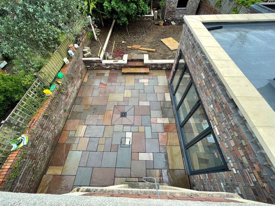A patio in mixed-colour riven slate beside a glazed single-storey extension