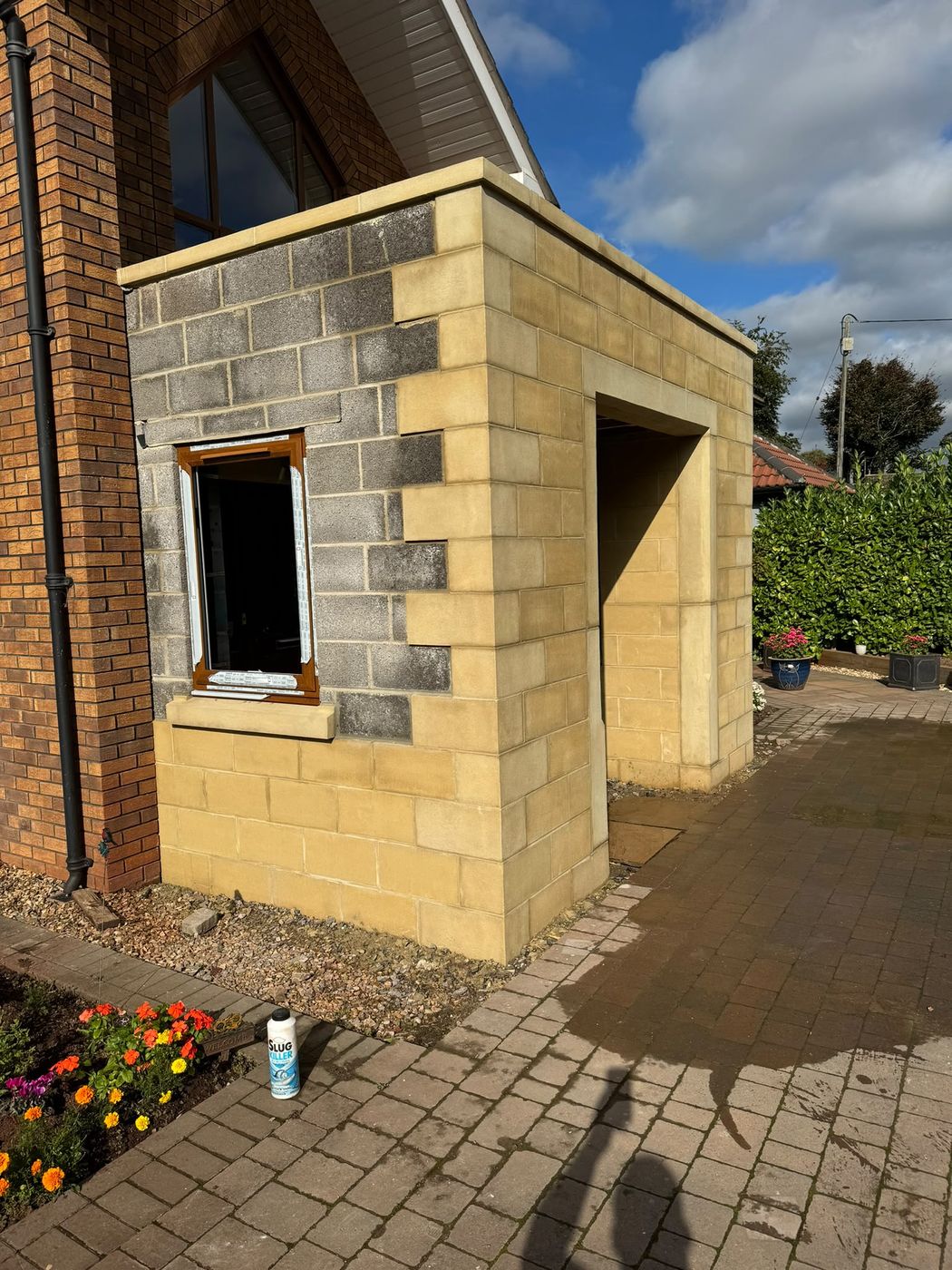 A single-storey extension going up in blockwork, with dressed stone
                quoins, cill and head around a new window and a doorway