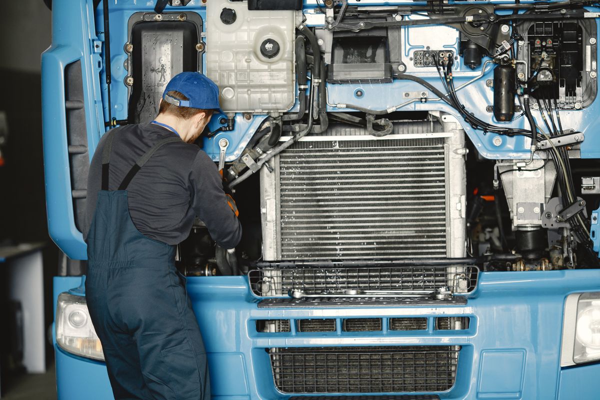 An engineer working on the engine of a blue lorry