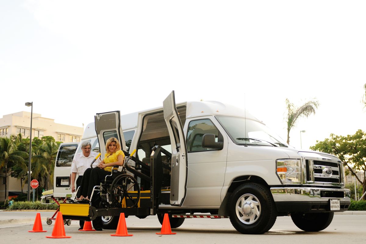 A wheelchair user boarding an accessible van on a yellow lift platform