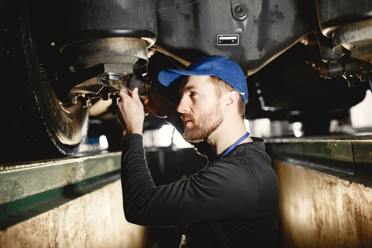 An engineer working underneath a vehicle over an inspection pit