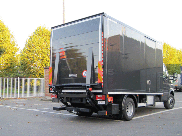 A cantilever tail lift folding down from the rear of a vehicle and lowering to the ground