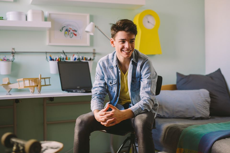 A smiling older student sitting in his room at home