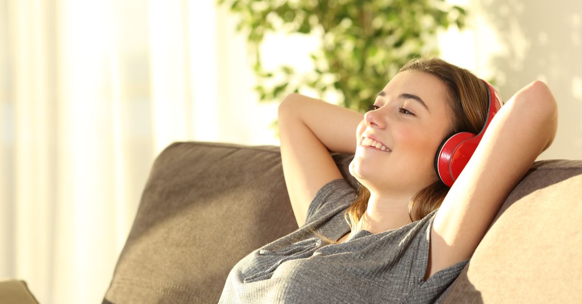 A happy girl relaxing on the sofa with headphones on