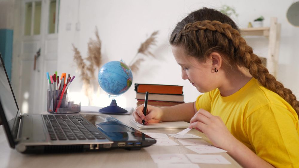 A girl writing at her desk beside a globe