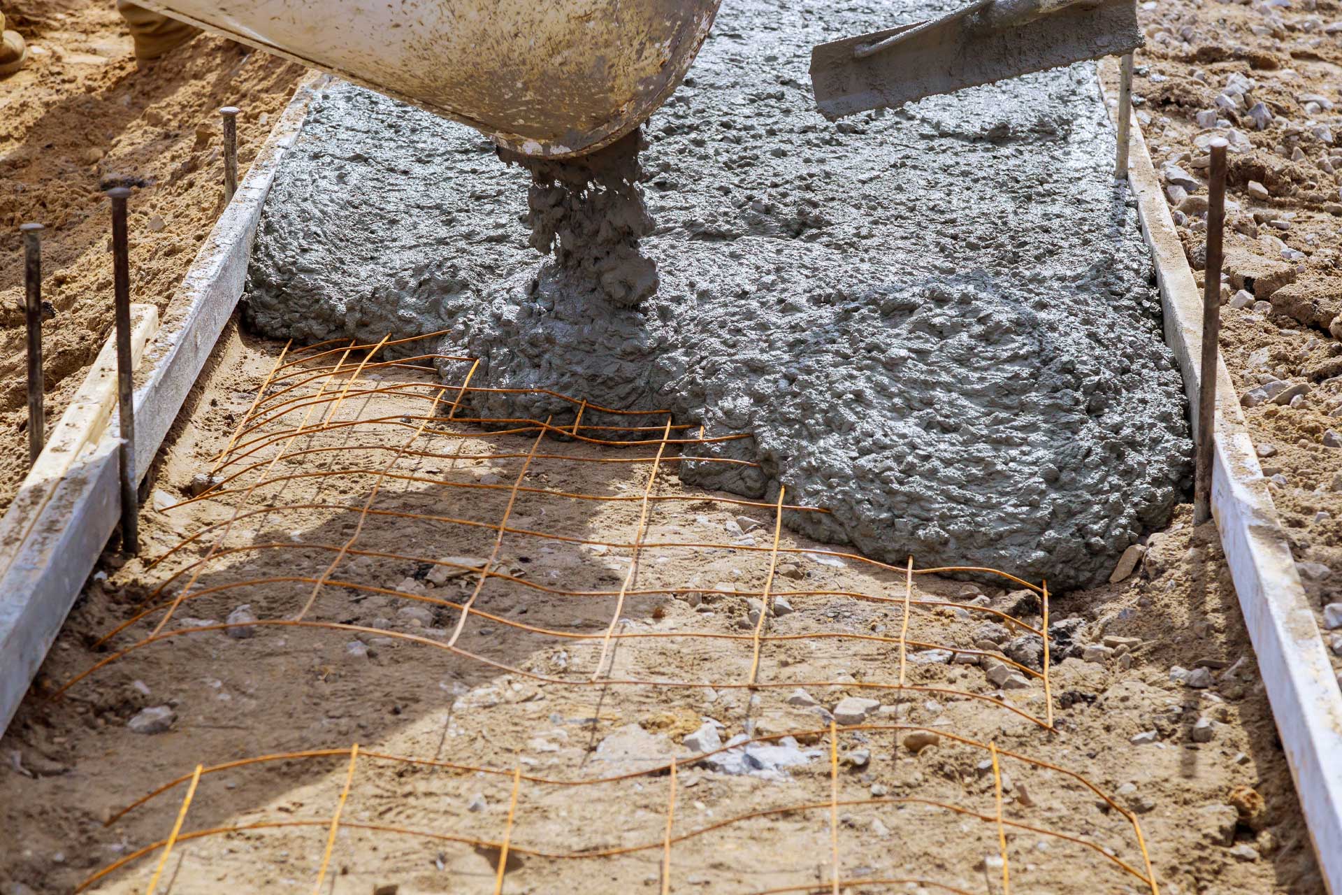 Concrete being discharged into a shuttered, mesh-reinforced foundation on a building site