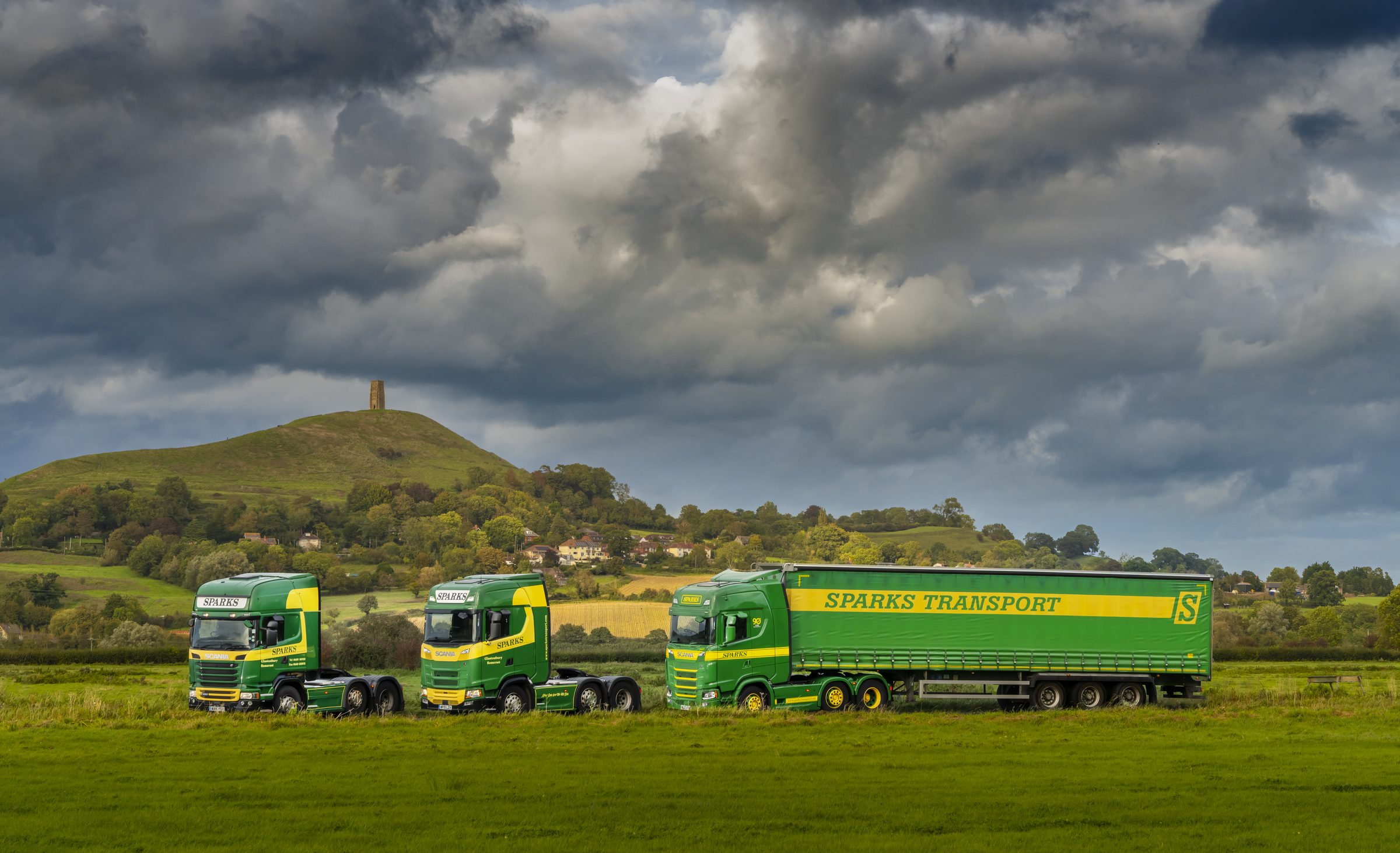 Three new Sparks Transport trucks — an Iveco, a Scania and a Volvo — in green and yellow livery outside the Glastonbury head office