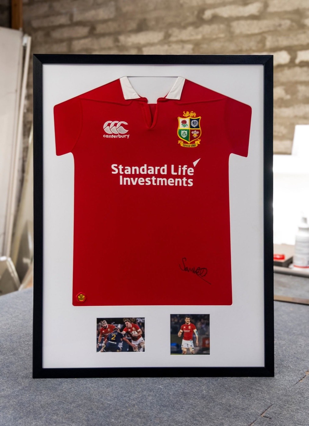 A signed rugby shirt box framed in black with two match photographs set into the mount
