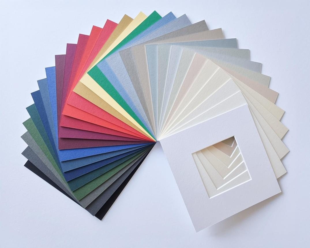 A fan of picture mounts in a range of colours, with a white bevel-cut mount in front